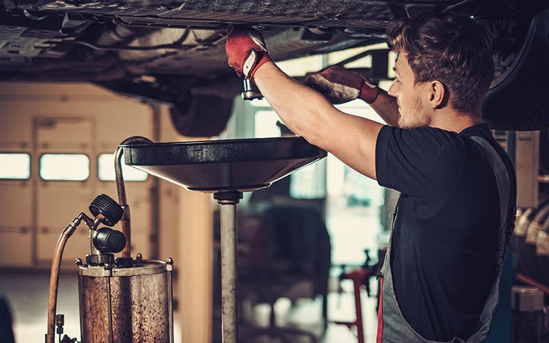 Service worker changing oil in car